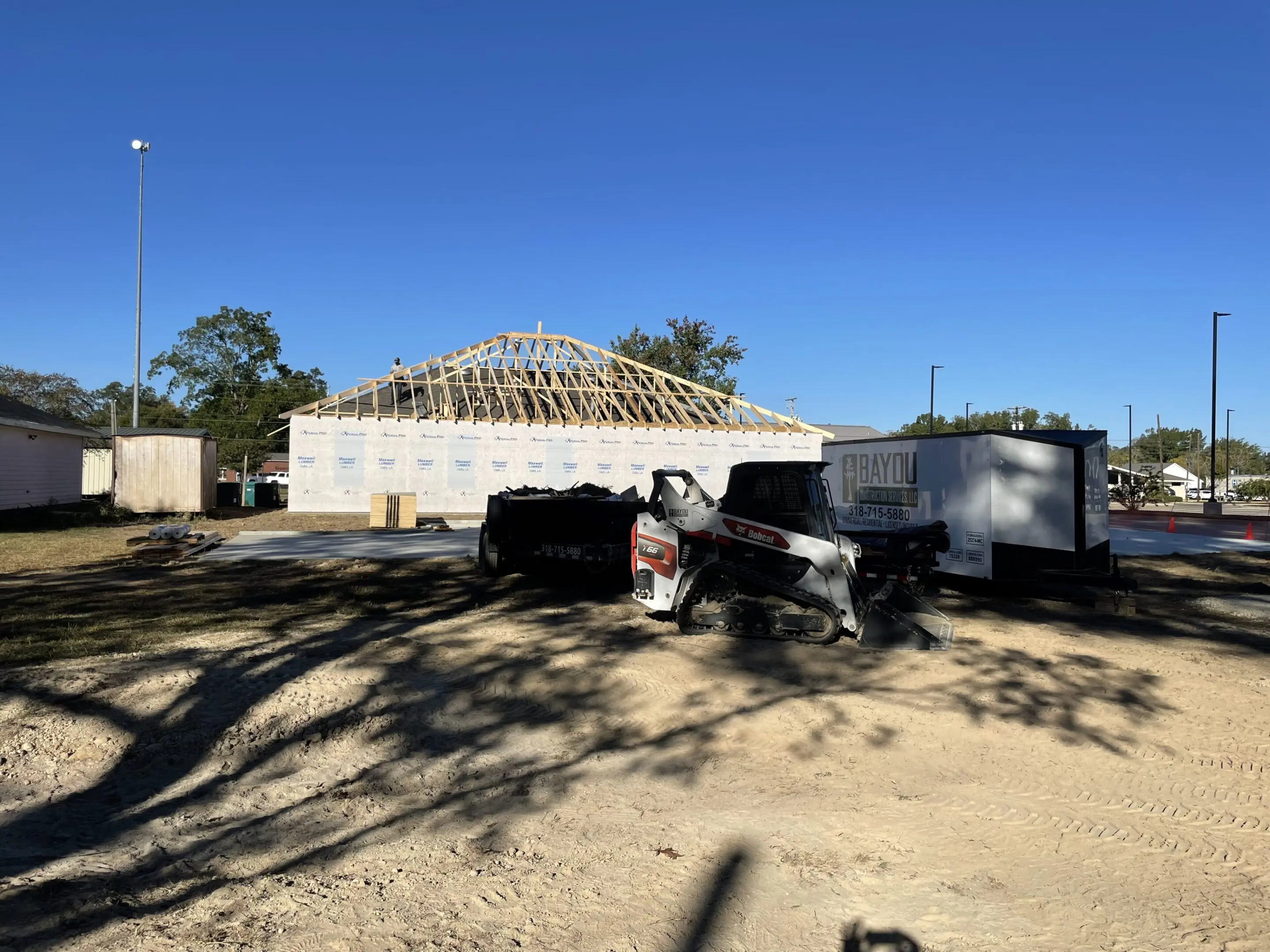 A truck parked in the sand near a building.