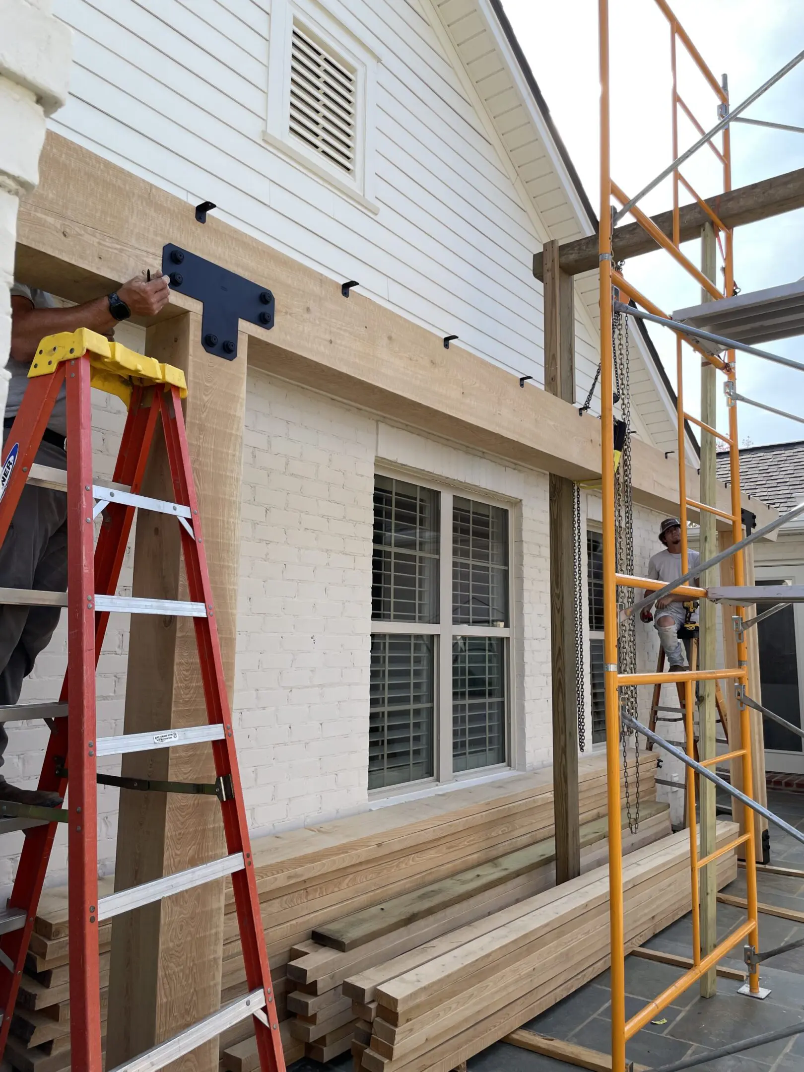 A man standing on a ladder next to a building.