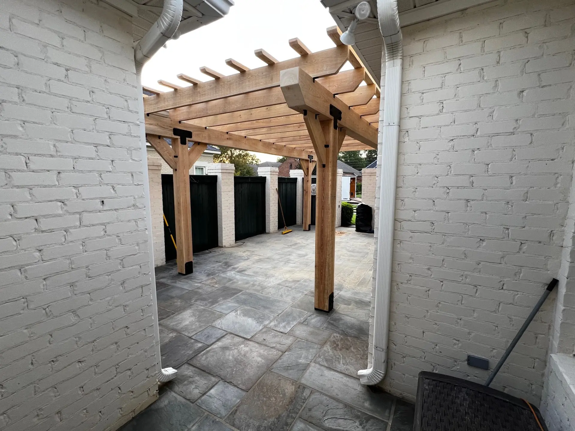 A brick wall with some doors and a wooden pergola