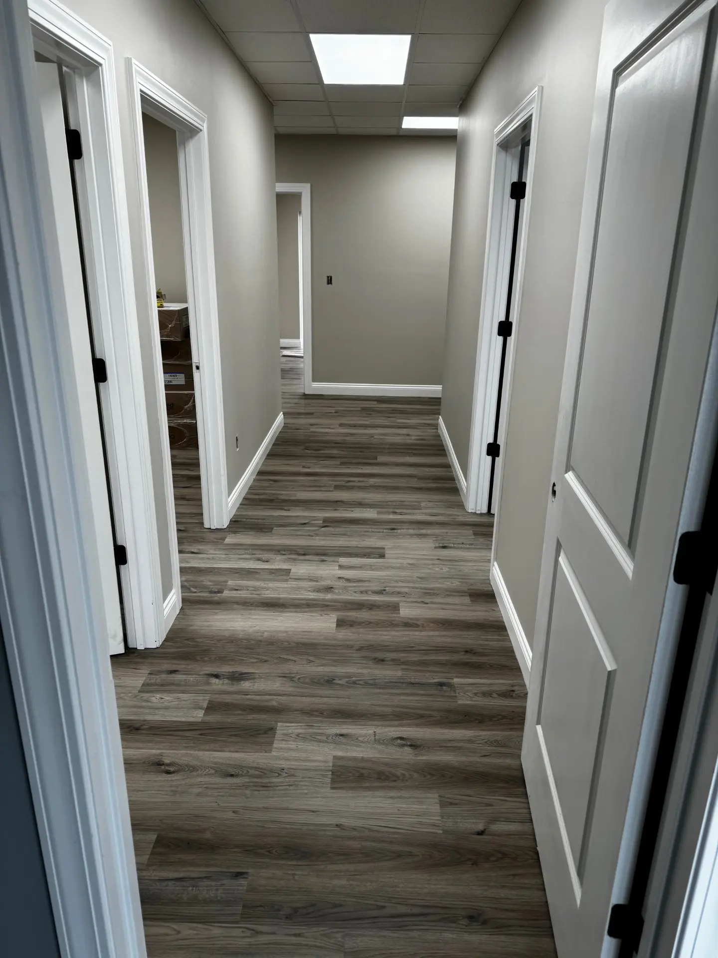 A hallway with two doors and wooden floors.