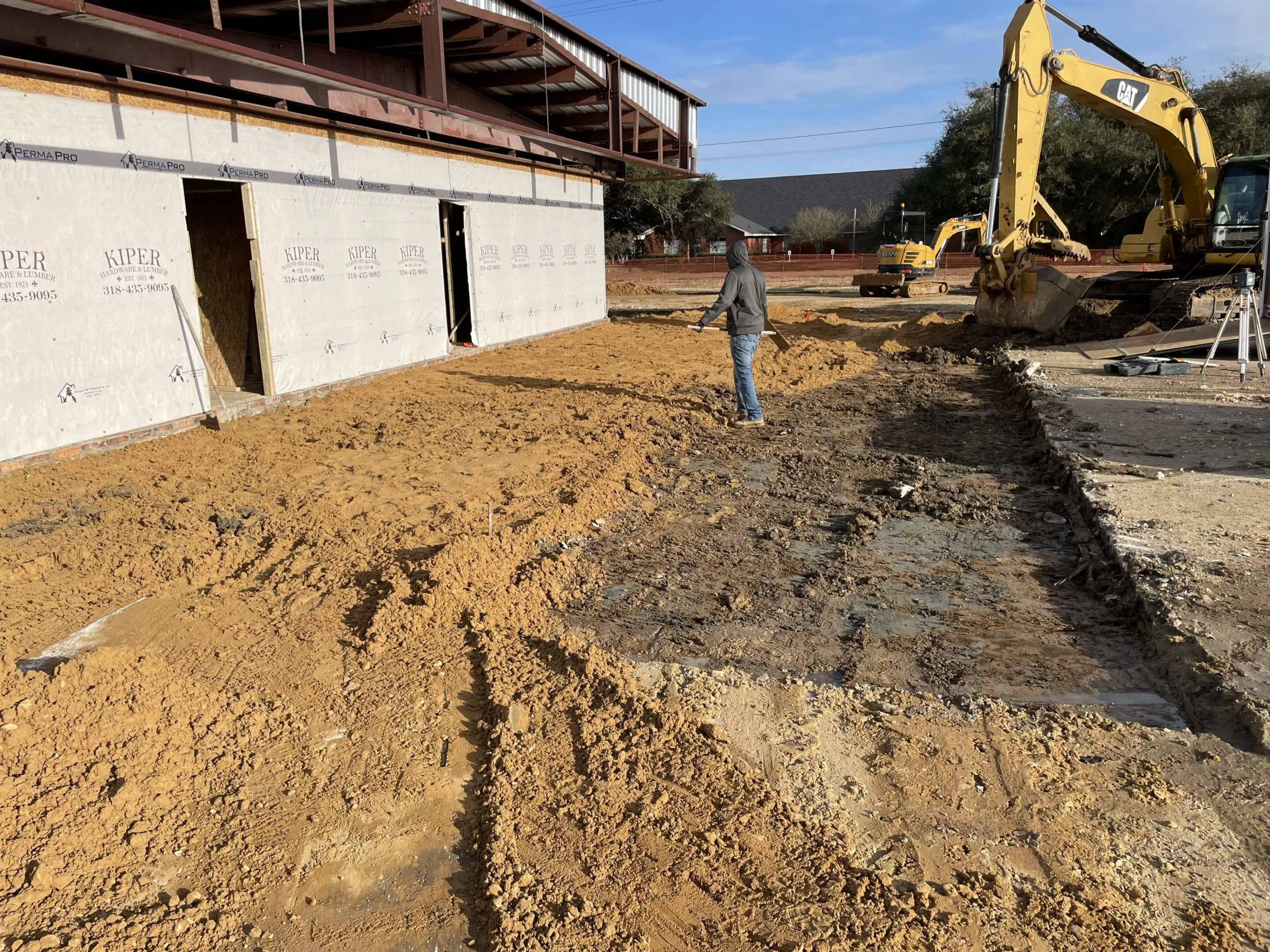 A fire hydrant is in the dirt near a building.