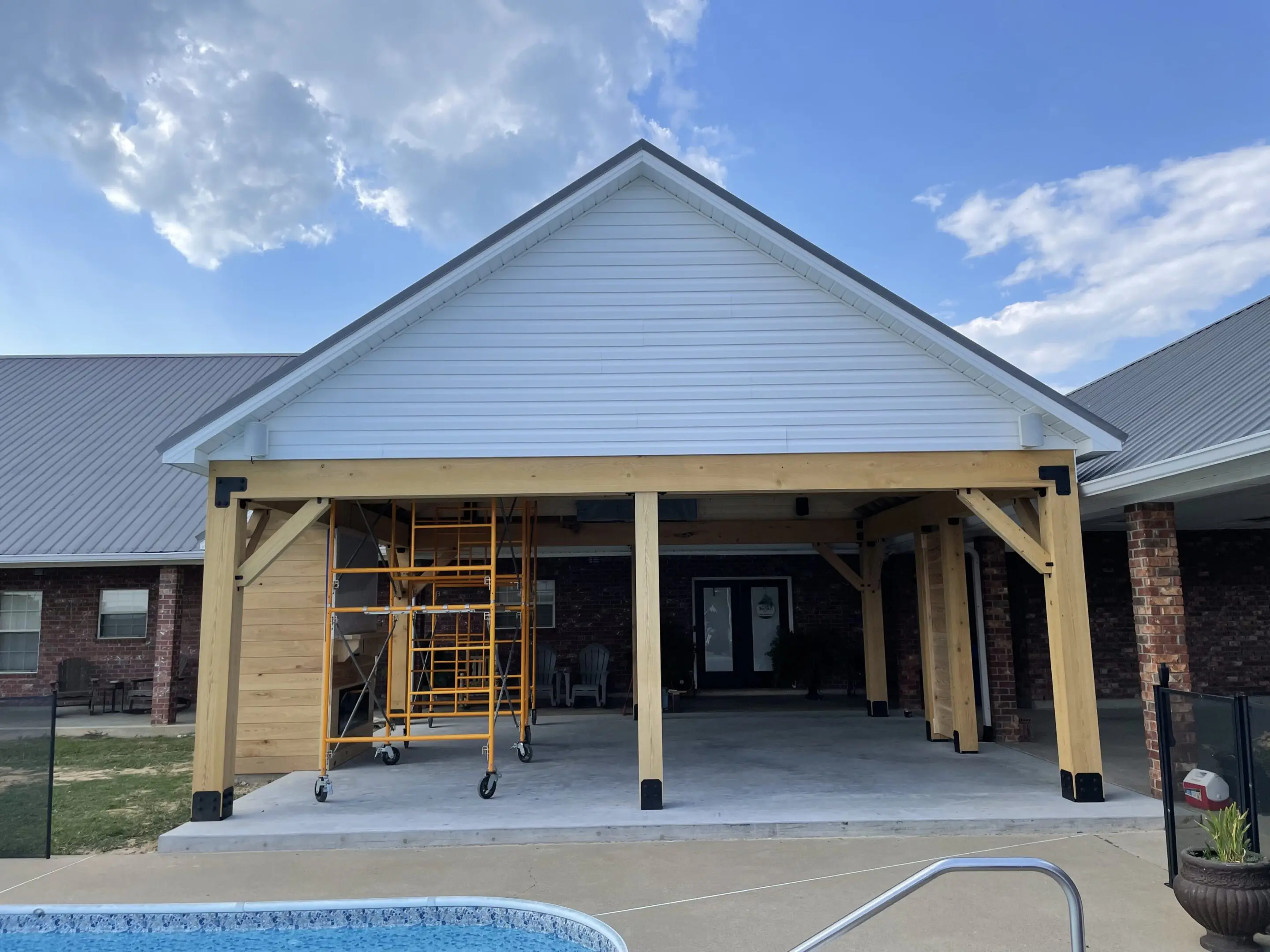 A house under construction with a pool in the foreground.