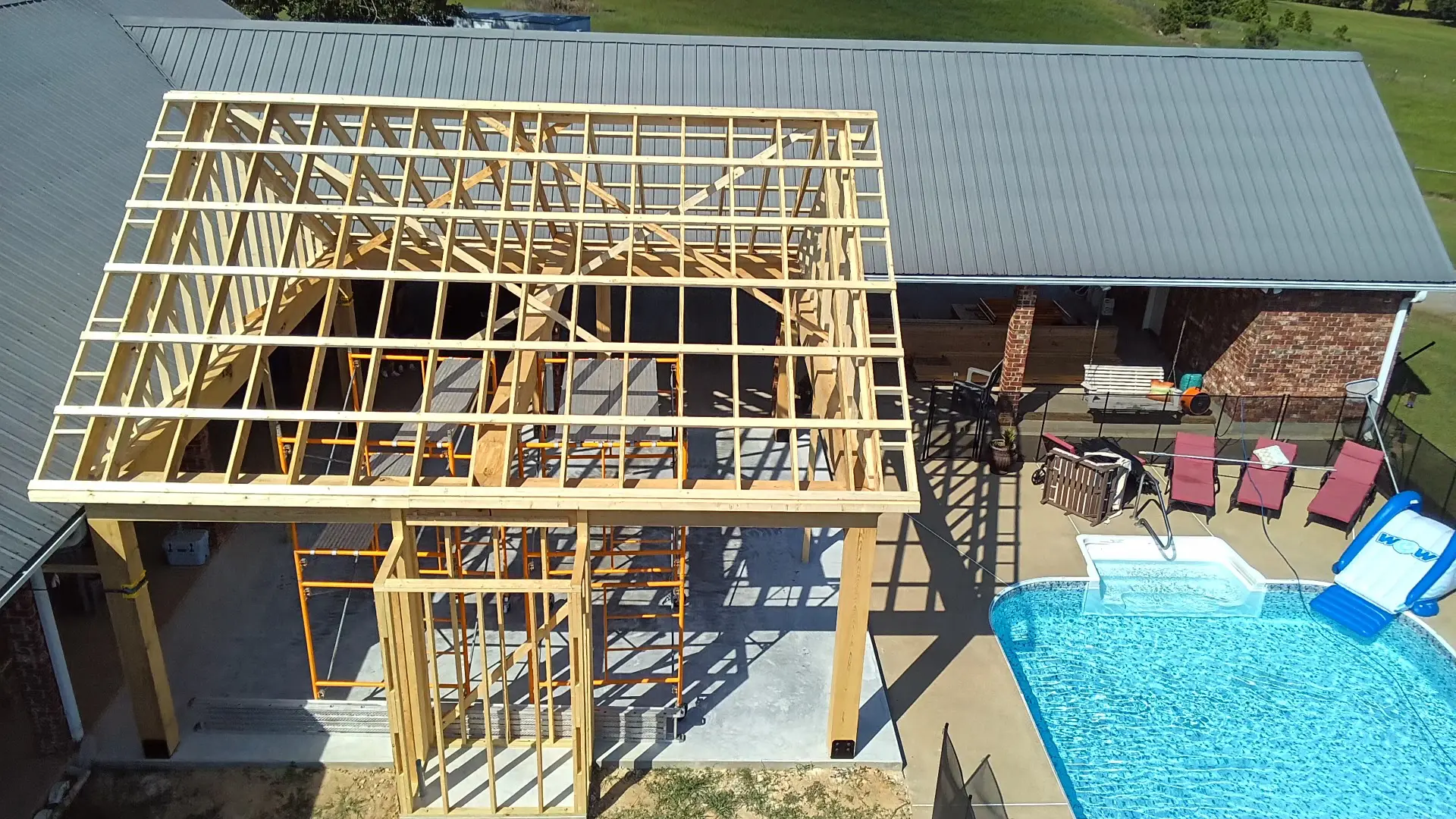 A building under construction with a pool in the background.